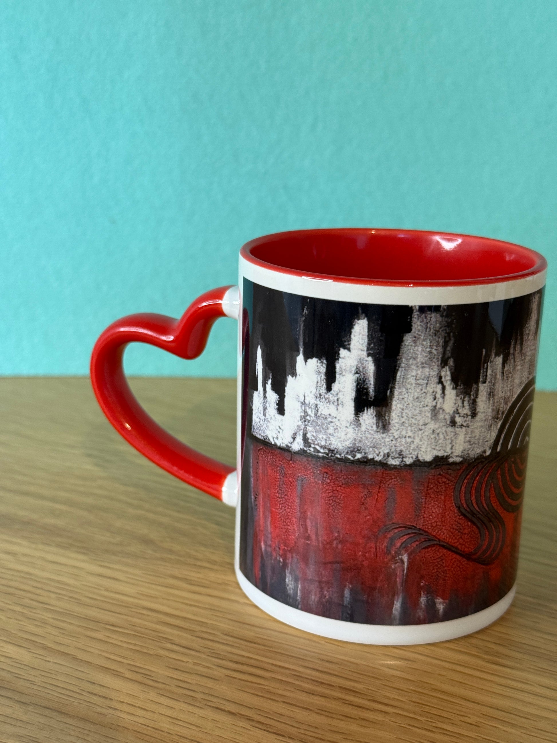 Herz Design Tasse schwarz-rot mit Skyline-Kunstmotiv und rotem Herzhenkel – türkiser Hintergrund
