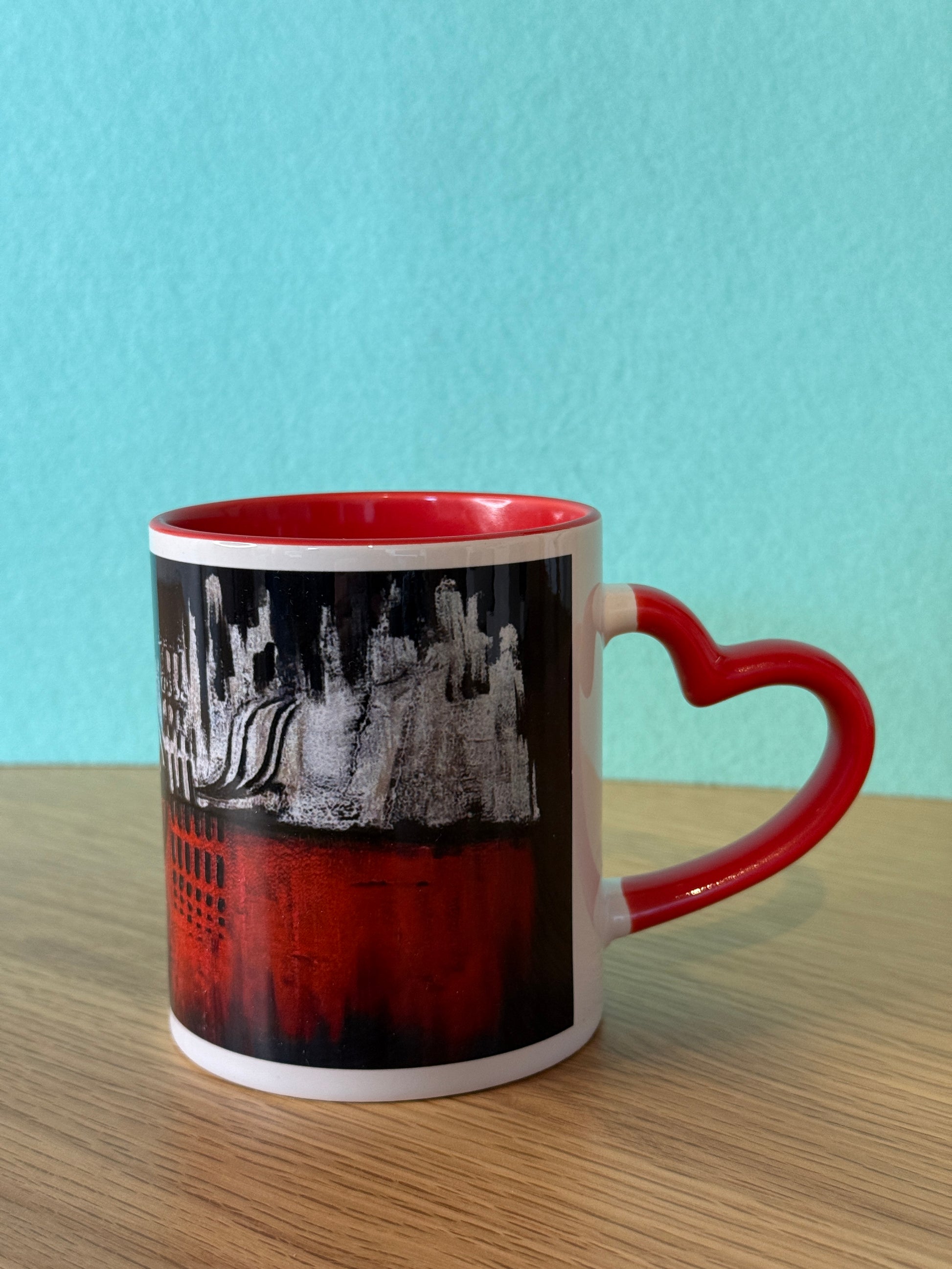 Herz Design Tasse schwarz-rot mit Skyline-Kunstmotiv und rotem Herzhenkel – türkiser Hintergrund