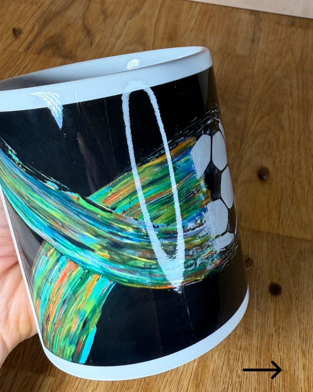Fußball Tasse mit buntem Kunstmotiv auf Holztisch – Vorderansicht mit Kaffeebohnen