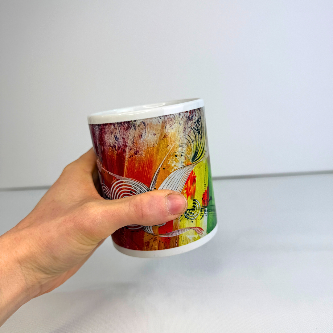 Hand hält Bunte Design-Tasse mit abstrakter moderner Kunst in kräftigen Farben.