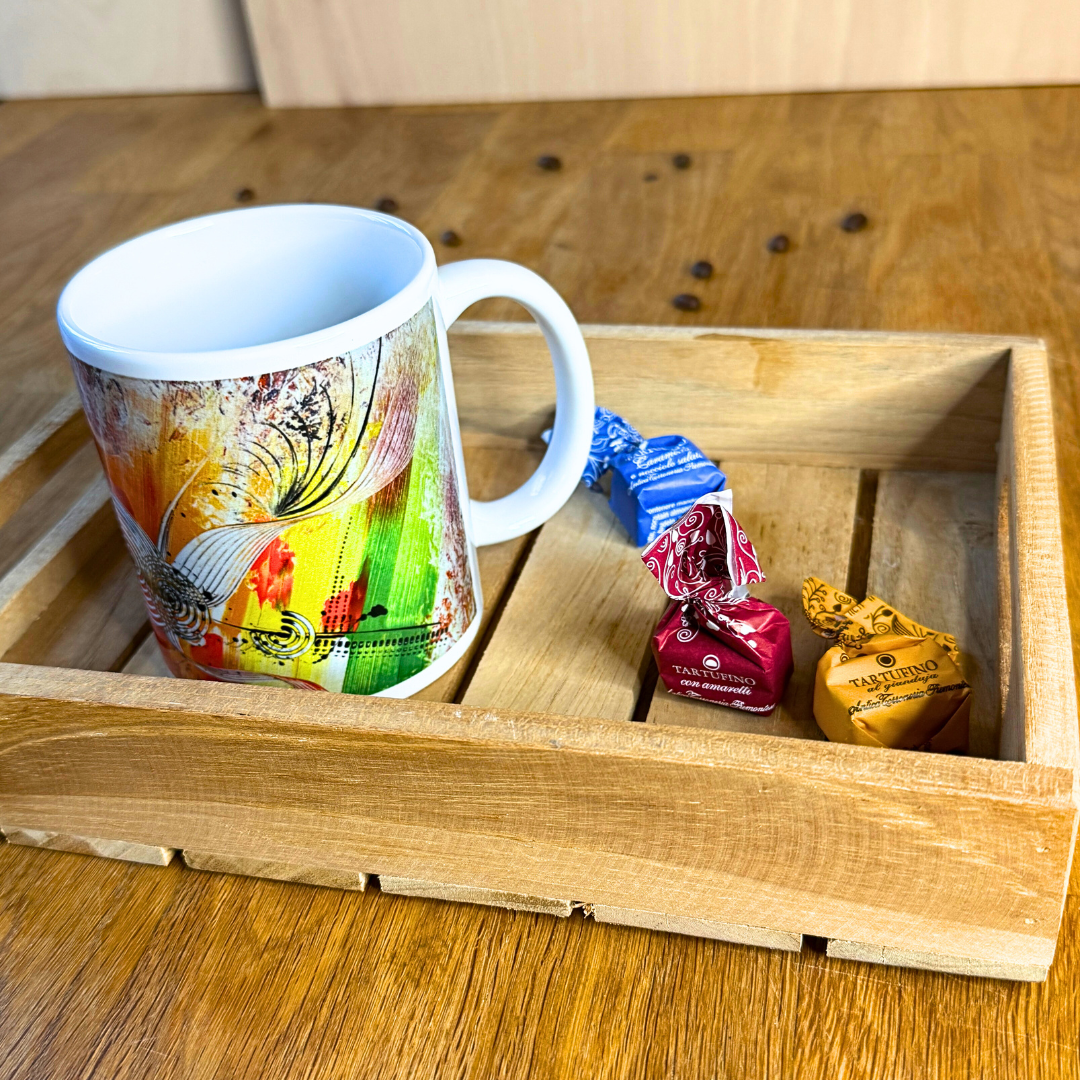 Bunte Design-Tasse mit abstrakter moderner Kunst in kräftigen Farben. Auf Tablett, das auf Holztisch steht.