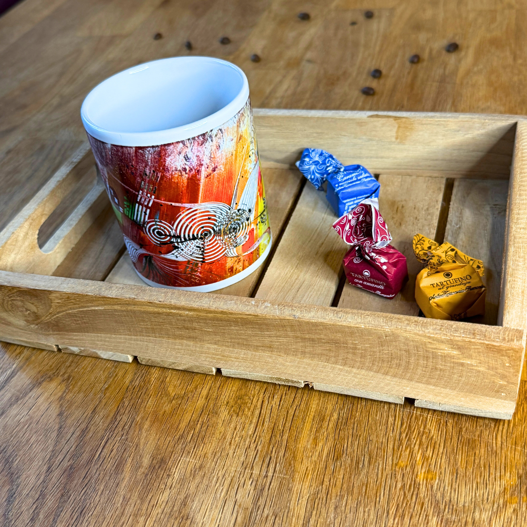 Bunte Design-Tasse mit abstrakter moderner Kunst in kräftigen Farben. Auf Tablett, das auf Holztisch steht.